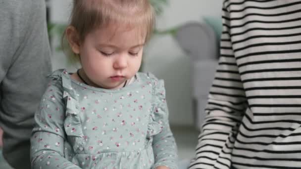 Lindo niño femenino despreocupado jugar con sus padres con constructor de color plástico mientras está sentado en la habitación de los niños — Vídeos de Stock