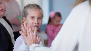 Kapsayıcı bir okulda ders sırasında Down sendromlu çocuklarla ders alan kız.