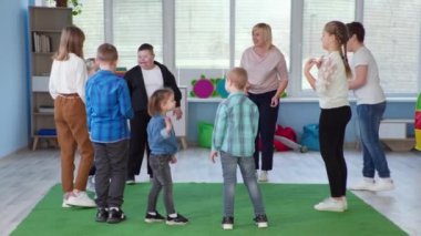 Bayan öğretmen Down sendromlu çocuklar için gelişim aktiviteleri düzenliyor ve top daireler çiziyor.