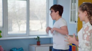 Engelli erkek çocuk Down sendromlu çocuklar için terapi sırasında kapsamlı bir sınıfta top oynarken eğleniyor.