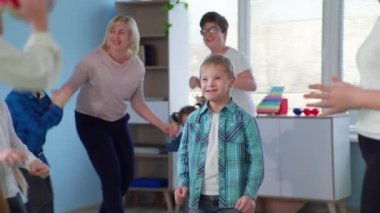 Down sendromlu çocuk engelli çocuklar için terapi sırasında kapsayıcı okulda top dersi verirken eğleniyor.