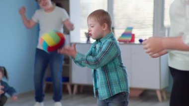 Erkek çocuk, Down sendromlu çocuklar için terapi yaparken eğleniyor. Kapsamlı bir okulda ders sırasında topla oynuyor.