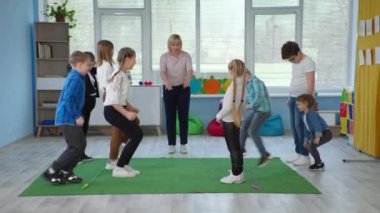 Kadın, kapsamlı bir okulda öğretmen olarak çalışıyor ve Down sendromlu çocuklar için dersler veriyor. Terapi sınıfında engelli çocuklar ip atlıyor.