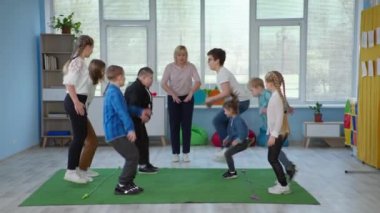 Down sendromlu çocuklar eğitim oyunları sırasında öğretmenleriyle birlikte ip atlarken eğlenirler.