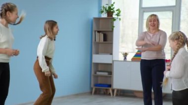 Çocuklar ders sırasında öğretmenleriyle ip atlıyor.