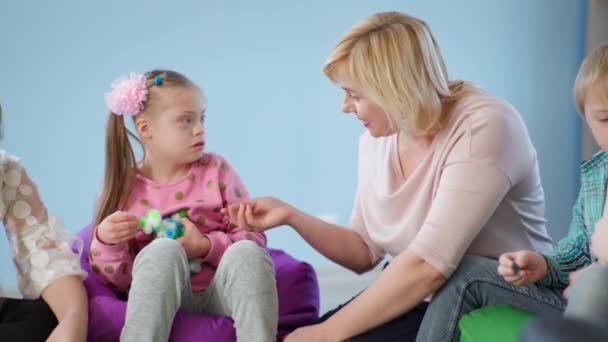Woman teacher conducts training sessions in inclusive classroom and establishes contact with girl with down syndrome — Stock Video