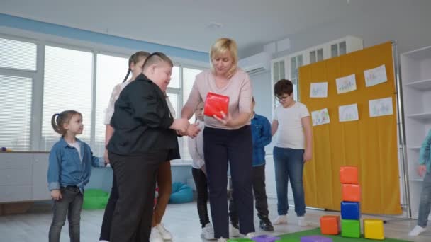 Adaptação social para crianças com deficiência, crianças felizes alegres se divertem brincando com uma professora — Vídeo de Stock