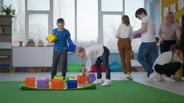 Barn i en inkluderande klass spela pedagogiska spel för barn med funktionshinder — Stockvideo