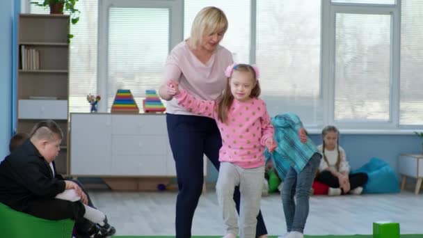 Maestra realiza capacitación y juega con niños con síndrome de Down durante la lección en una escuela inclusiva — Vídeos de Stock