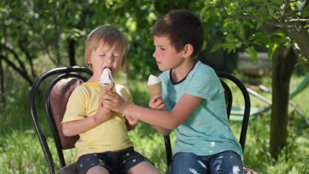 Anak laki-laki riang makan es krim dingin yang lezat di sore musim panas yang hangat sambil bersantai — Stok Video
