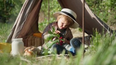 Piknikteki çocuk, elinde kiraz filizi olan hasır şapkalı şirin çocuk şehir dışında dinlenirken eğleniyor.