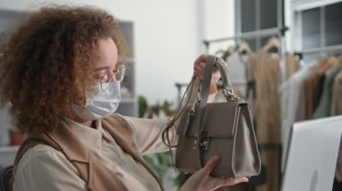 Küçük işletme, koruyucu maskeli genç bir kadının portresi internet üzerinden mal satışı video iletişimi, gülümseme ve karantinada çalışırken kameraya bakma yoluyla internet üzerinden iletişim kuruyor.