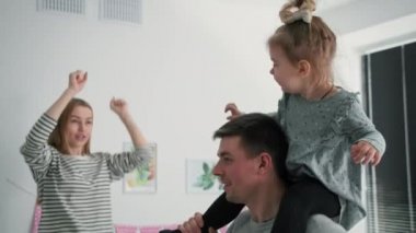 Ebeveynler, neşeli ebeveynler, sevimli kızlarıyla birlikte, aile eğlencesi sırasında aktif olarak oynuyorlar ve atlıyorlar.