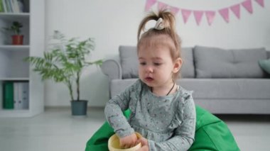 Kaygısız bir çocukluk, sağlıklı üzüm yiyen küçük tatlı bir kız yumuşak bir çocuk koltuğunda oturuyor.