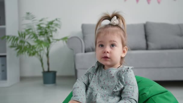 Retrato de uma criança bonita do sexo feminino com apetite come uvas suculentas lardy enquanto sentado em uma poltrona macia em casa — Vídeo de Stock