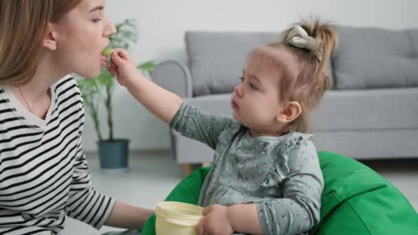 Maternidad, linda hija pequeña alimenta a su madre con uvas dulces, cuidado padre femenino beso niña en la frente mientras se relaja en casa — Vídeos de Stock