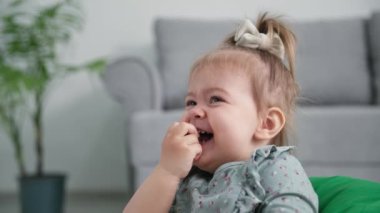 Bebeklik, iştahlı gülümseyen kadın çocuk yemek için olgun üzümler yer ve oturma odasındaki kanepede otururken güler.