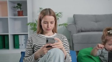 Aile ilişkileri, genç karı koca birlikte. Küçük bir kız evde dinlenirken sosyal ağlarda iletişim kurmak için akıllı telefon kullanıyor.