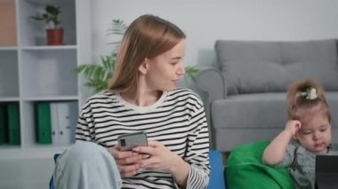 Ebeveynler ve çocuklar arasındaki iletişim, küçük kızıyla birlikte genç baba ve anne evde dinlenirken sosyal ağlarda iletişim kurmak için akıllı telefonlar kullanıyor.