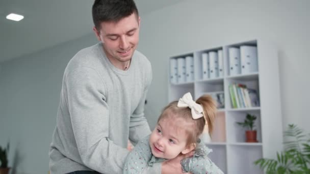 Parenting, father has fun with daughter rolling in his arms during family vacation at home — Stockvideo