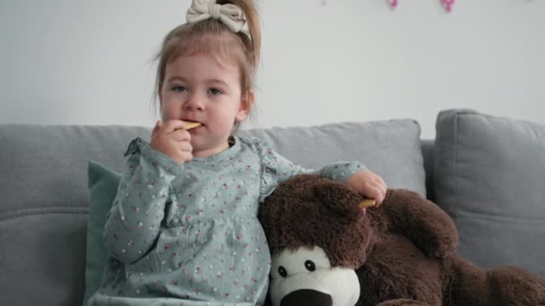 Parent-child relationship, loving woman sits on daughters sofa, little girl feeds her mom with cookies in living room — Stockvideo