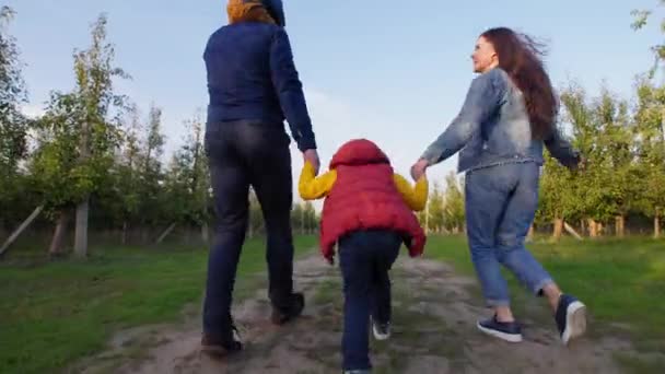 Aktivní rodina, rodiče se syny držícími se za ruce běží podél venkovské silnice — Stock video
