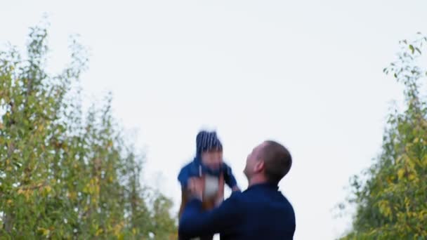 Far leker en lykkelig far kaster opp glad baby mens han går ute i hagen – stockvideo