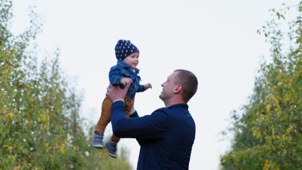 Paternité, l'homme s'amuse avec un petit enfant mâle en le jetant lors d'une promenade en plein air dans le jardin — Video