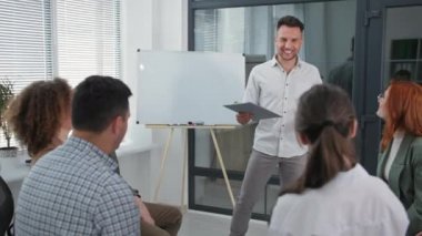 İş eğitimi, genç erkek konuşmacı çalışma takımının ellerini bir araya topluyor. Psikolojik seans sırasında yukarı ve aşağı eğilip alkışlıyorlar.