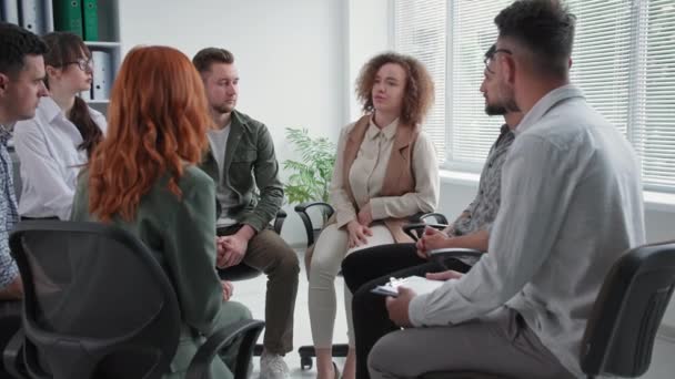 Grupo de apoyo, una joven encantadora habla y comparte sus experiencias emocionales frente a las personas durante el entrenamiento — Vídeo de stock