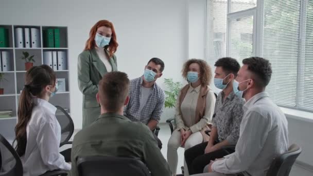 Therapie sessies tijdens quarantaine, jonge groep van mensen met medische maskers praten over hun problemen en applaudisseren elkaar tijdens gezamenlijke psychologische training — Stockvideo