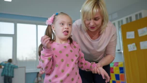 Vrouw voert ontwikkelingsactiviteiten met meisje met een handicap tijdens de les in een inclusieve klasse — Stockvideo