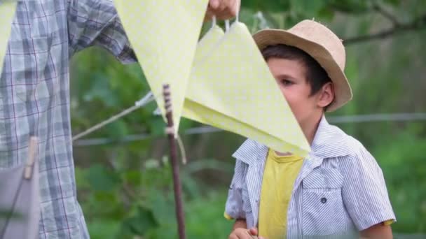 Enfance insouciante, petit-fils joyeux s'amuse avec son grand-père aimant et accrocher des drapeaux de couleur pendant les loisirs en plein air — Video