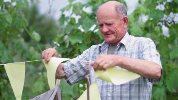 Parent, soignant vieil homme aide à décorer tipi dans le jardin avec des drapeaux de fête sur la chaude journée d'été — Video