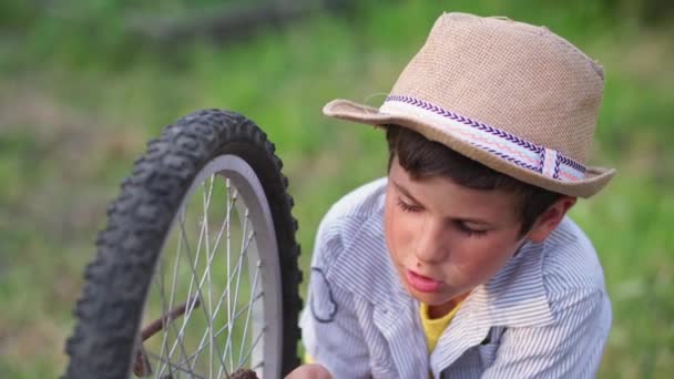 Summer vacation, adorable male child in sun hat repairing bicycle wheel together with grandfather, close-up — Stock Video