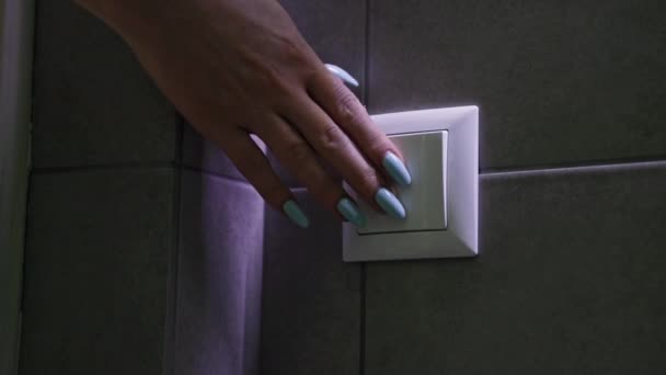 Energía eléctrica, las mujeres jóvenes apagan la luz del baño después de su uso con interruptor en la pared, primer plano — Vídeos de Stock