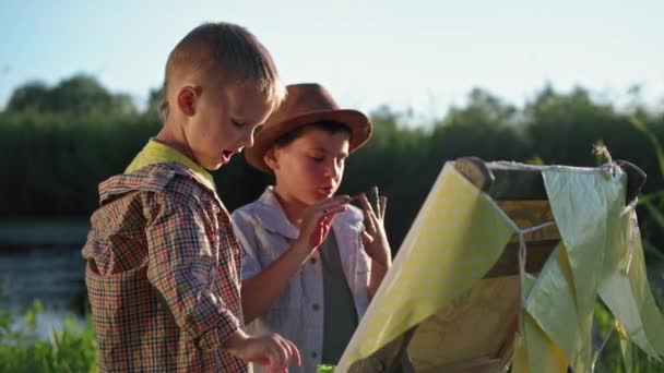 Desenvolvimento de crianças, irmãos se divertir desenho com tintas nas palmas das mãos e colocar impressões digitais em papel enquanto descansa ao ar livre perto do rio e juncos — Vídeo de Stock