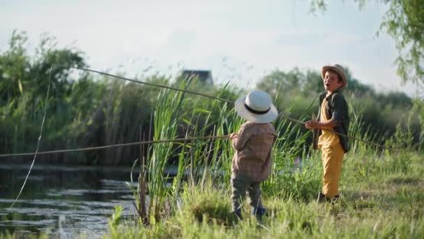 Милий чоловік діти в капелюхах весело рибалити в річці, використовуючи рибальські палички, перебуваючи поза містом літні канікули — стокове відео