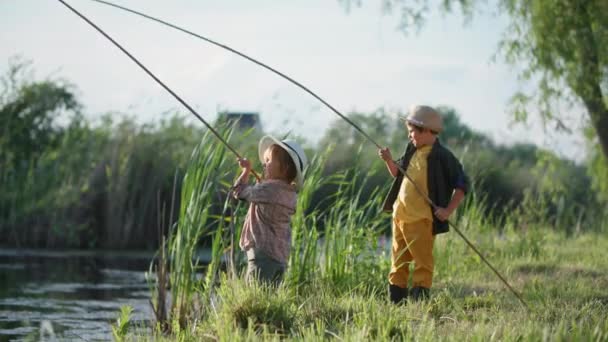 Kleine männliche Fischer mit Hüten haben Spaß beim Angeln mit der Rute im Fluss während eines Familienwochenendes im Dorf — Stockvideo