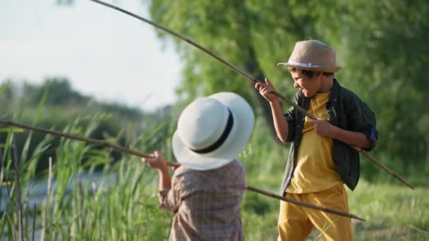 Recreação ao ar livre, crianças felizes do sexo masculino com varas de pesca em suas mãos peixe no fundo do lago de árvores e juncos durante um fim de semana fora da cidade — Vídeo de Stock