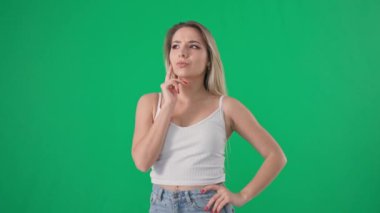 Uzun saçlı, düşünceli, çekici bir genç kadının portresi yeşil arka planda, krom anahtarla başını çeviriyor.