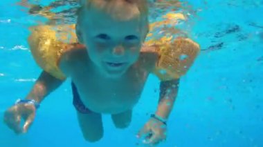 brothers swims with open eyes in blue water of pool during summer holiday, children dives under water together