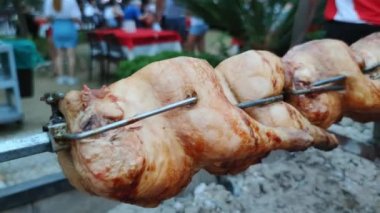 food festival, roasted chickens in rotating skewer on charcoal grill closeup