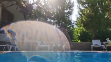 Aktif mutlu adam takla atarak mavi havuza atlıyor yaz tatilinde, su altında atış ve hava kabarcıkları