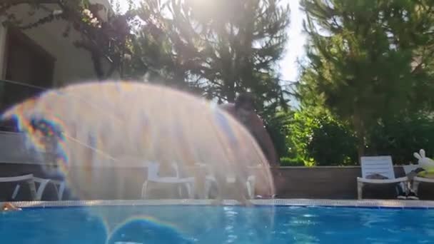Aktywny szczęśliwy człowiek skacze z salta do niebieskiego basenu podczas wakacji, podwodne strzelanie i pęcherzyki powietrza — Wideo stockowe