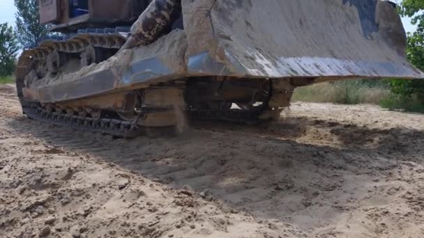 Movedor de terra pesada, escavadora de esteiras rolantes dirigindo na estrada arenosa, vista de perto na máquina bulldozer — Vídeo de Stock