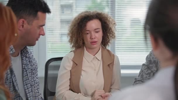 Retrato de una joven compartiendo sus problemas y experiencias emocionales durante la terapia de grupo sentada en un círculo — Vídeos de Stock