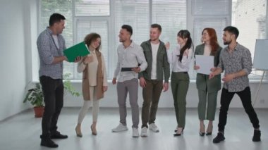 İş ekibi, neşeli erkek ve bayan meslektaşlar iyi haberlerle eğlenin atlama ve ofiste gülme