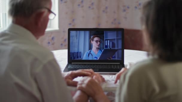 Assistenza medica, vista posteriore della coppia anziana che guarda lo schermo del computer portatile e parla con il medico tramite videochiamata — Video Stock