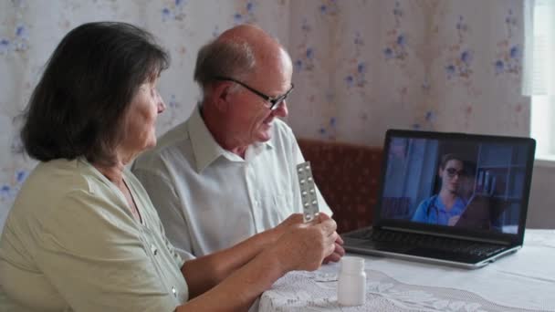 Pacientes utilizan videollamada de conferencia con médico femenino, terapeuta virtual consultando pareja mayor durante la cita en línea en el ordenador portátil en casa — Vídeos de Stock